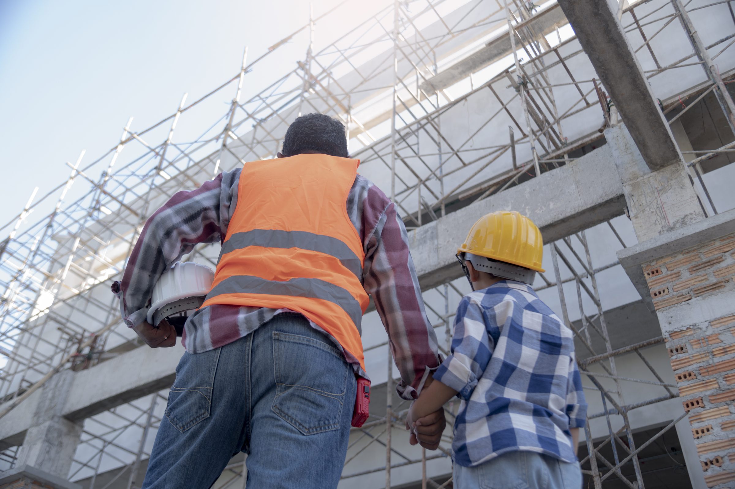 A parent and child looking up at a building under construction